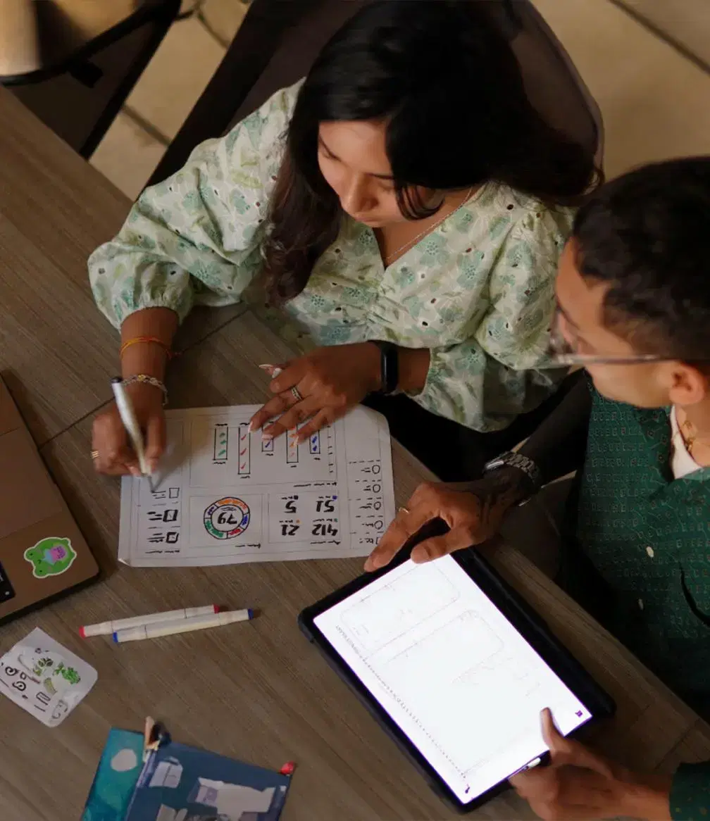 One employee on a tablet, another sketching on paper, bringing client ideas to life through prototypes and low-fidelity designs.