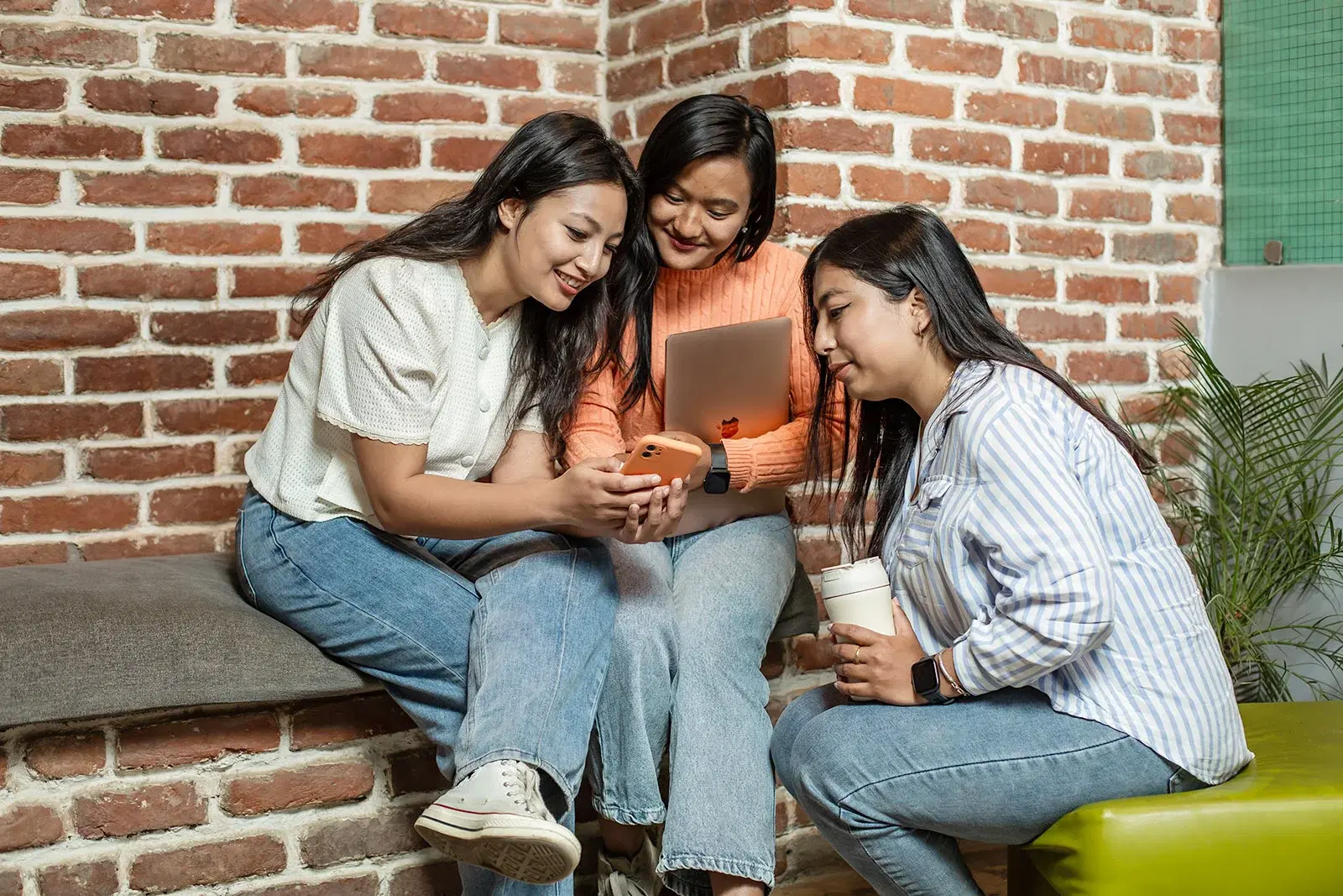 Three female employees engaged in friendly conversation in a lobby area.