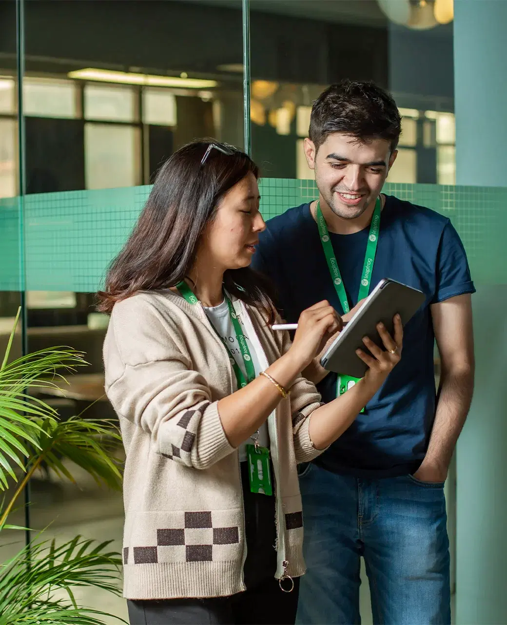 Two employees, one female, and one male, standing and using a tablet for collaborative brainstorming as the female presents her ideas.