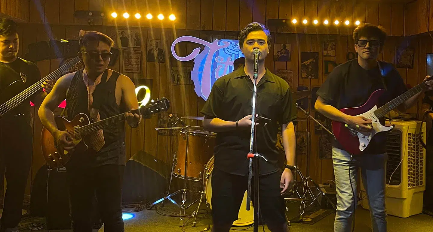 One person singing, three playing guitars at a rock night event.