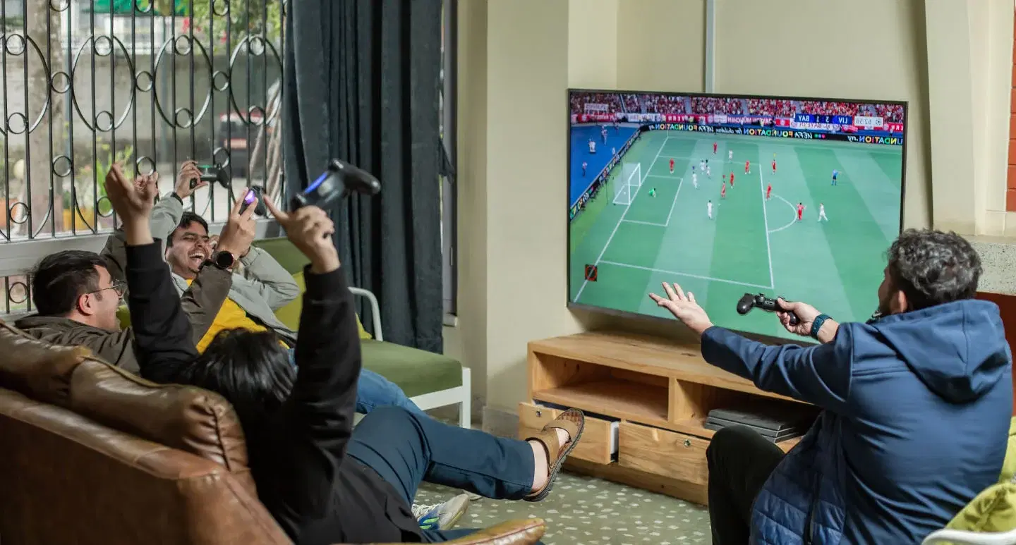 Four employees playing FIFA in an office game zone, sharing smiles and celebrating victories.